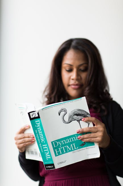 The image shows a woman with long dark hair and medium skin tone reading a book titled 'Dynamic HTML' by O'Reilly, which features a black-and-white illustration of a flamingo on the cover. She is wear